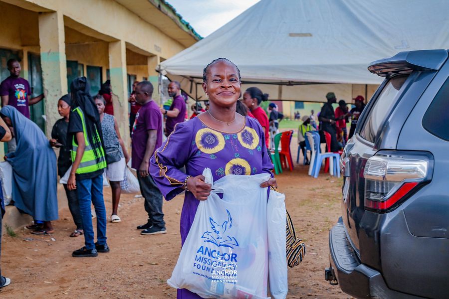 A woman smiling while holding an Anchor Missionary Foundation relief bag