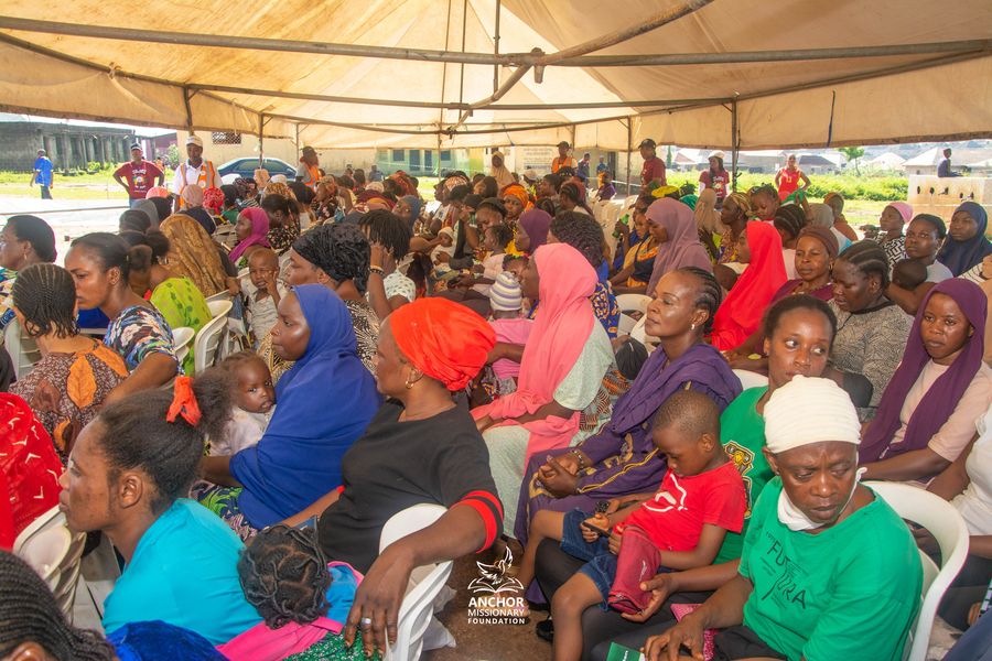Women and children seated under a tent at an Anchor Missionary Foundation community health outreach